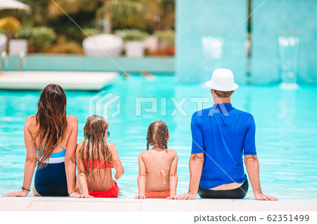 Happy family of four in outdoors swimming pool Happy family of four in outdoors swimming pool 62351499