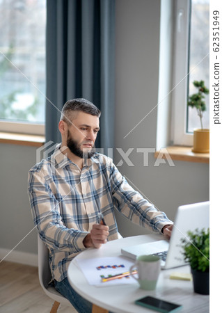 Young man sitting at the table distracted from work. 62351949