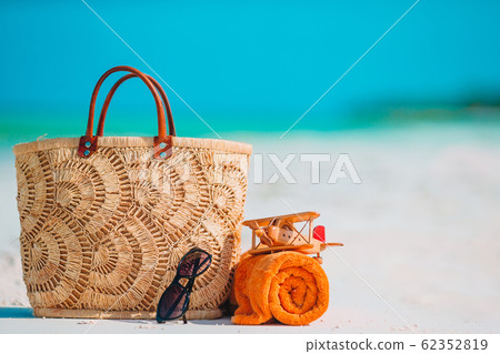 Beach accessories - bag, straw hat, sunglasses on white beach 62352819
