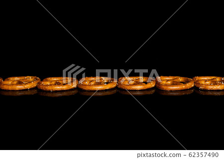 Salty brown pretzel isolated on black glass Salty brown pretzel isolated on black glass 62357490