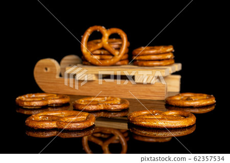 Salty brown pretzel isolated on black glass Salty brown pretzel isolated on black glass 62357534