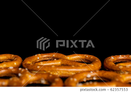 Salty brown pretzel isolated on black glass Salty brown pretzel isolated on black glass 62357553