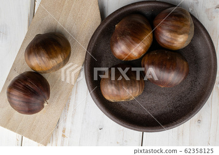 Brown edible chestnut on grey wood Brown edible chestnut on grey wood 62358125