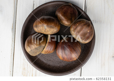 Brown edible chestnut on grey wood Brown edible chestnut on grey wood 62358131