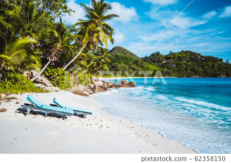 Mahe, Seychelles. Beautiful Anse intendance, tropical beach with relaxing lounger. Blue ocean, sandy beach and coconut palm trees. Travel concept 62358150
