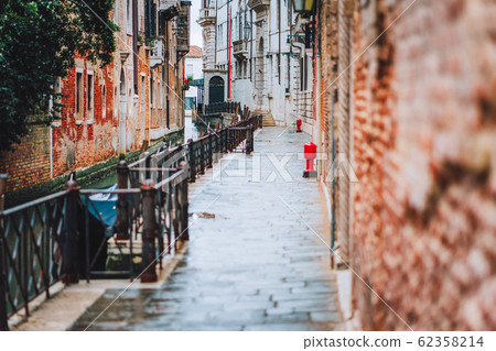 Venice, Italy. The small streets and narrow channel with colored brick houses on the shore of old city Venice, Italy. The small streets and narrow channel with colored brick houses on the shore of old city 62358214