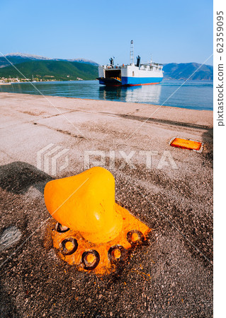 Orange Mooring Bollard and big ferry boat with passengers and cars arrives beautiful greek island. Summer vacation 62359095