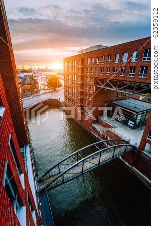 HafenCity. Bridge over canal and red brick buildings in the old warehouse district Speicherstadt in Hamburg in golden hour sunset light, Germany. View from above 62359112