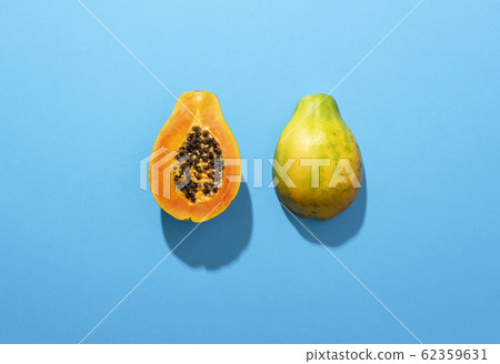 Ripe papaya fruit cut in half on blue background 62359631
