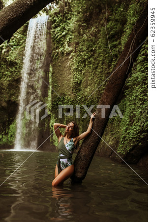 Beautiful sexy girl under a waterfall in Indonesia. 62359945