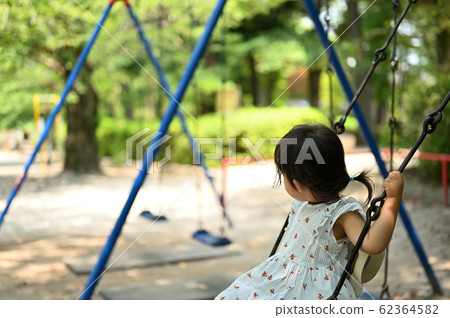 A girl playing with a swing in a park 62364582
