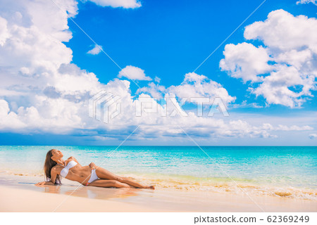 Beach travel vacation paradise sexy bikini woman lying down on sand relaxing sun tanning in tropical caribbean travel destination for summer vacation. Asian swimsuit model girl Beach travel vacation paradise sexy bikini woman lying down on sand relaxing sun tanning in tropical caribbean travel destination for summer vacation. Asian swimsuit model girl 62369249