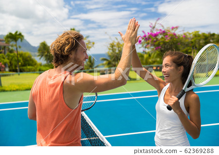 Fitness sport tennis couple giving high five energetic after fun mixed double game. Tennis players friends having fun doing fit sport at hotel ,summer travel vacation. Asian woman, Caucasian man 62369288