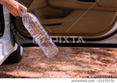 Woman hand holding plastic bottle on the road,Global warming environmental protection concept Woman hand holding plastic bottle on the road,Global warming environmental protection concept 62370576
