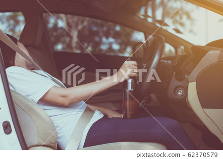 Drunk asian woman drinking alcohol and sleeping while driving car,Women drive her car with a bottle of beer 62370579