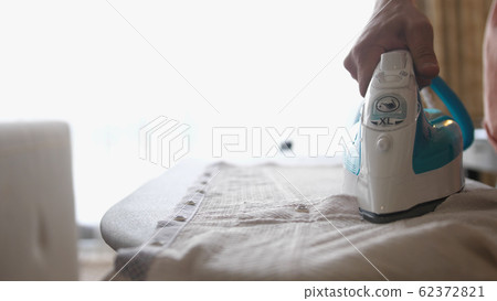 Close up of male hands ironing clothes with iron on an ironing board. slow motion 62372821