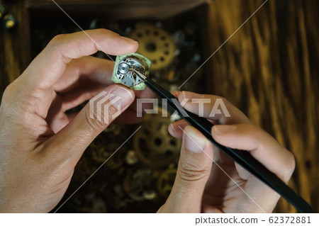 Girl craftsman dismantles clocks. 62372881