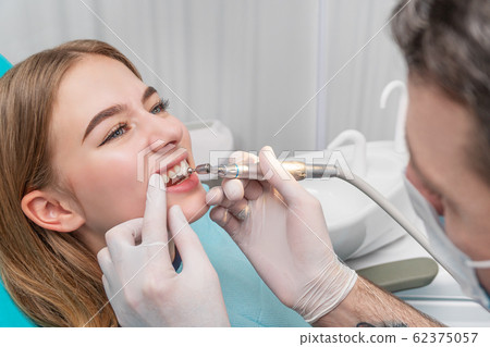 Dentist polishes patient teeth 62375057