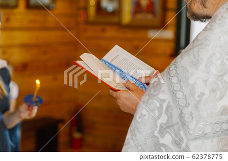 Old priest hands on the bible in the church at the 62378775