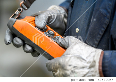 Male hand push remote control switch for overhead crane in the factory, close-up. Electrical control Male hand push remote control switch for overhead crane in the factory, close-up. Electrical control 62379067