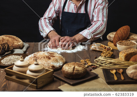 Close up of baker hands kneading dough and making bread with a rolling pin. 62383319