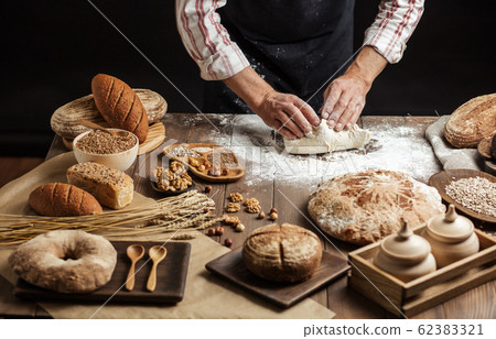 Close up of baker hands kneading dough and making bread with a rolling pin. Close up of baker hands kneading dough and making bread with a rolling pin. 62383321