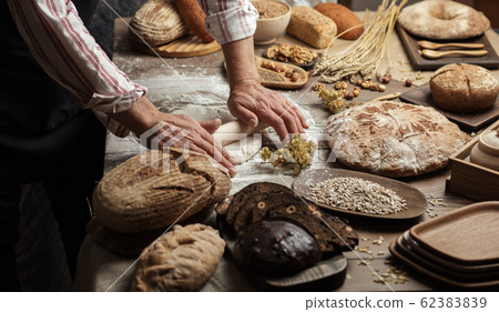 Man rolling out dough on kitchen table, close up Man rolling out dough on kitchen table, close up 62383839