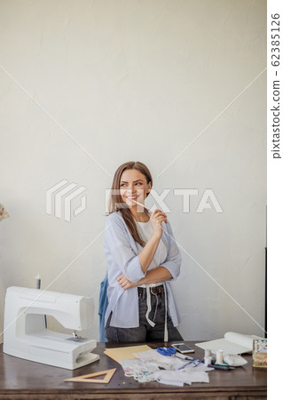 Close-up portrait of young seamstress or dressmaker a her workplace. Close-up portrait of young seamstress or dressmaker a her workplace. 62385126