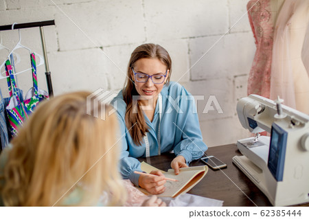 Female seamstress discussing features of the order with client in cozy studio 62385444