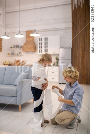 Two kids playing toilet paper mummy game at home and feeling good Two kids playing toilet paper mummy game at home and feeling good 62388943