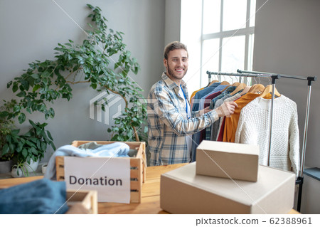 Young man standing at a rack with clothes. 62388961