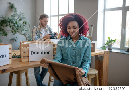 Joyful young girl with brown pullover in her hands. Joyful young girl with brown pullover in her hands. 62389201