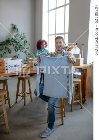 Young man with a white sweater in his hands. Young man with a white sweater in his hands. 62389207