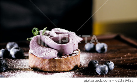 Cake with purple cream on the table near the blueberries, close-up. 62389453