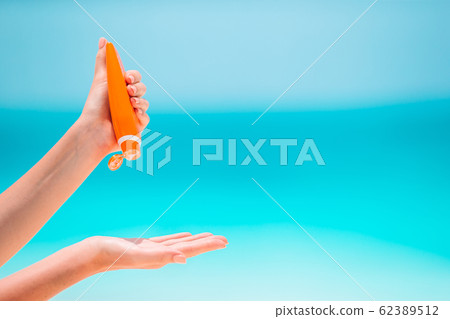 Beautiful young woman holding a suncream lying on tropical beach 62389512