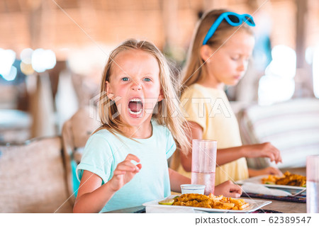 Adorable little girl having breakfast at outdoor cafe 62389547