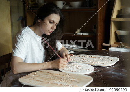 Woman brush the relief pattern obtained from the mold for casting clay products Woman brush the relief pattern obtained from the mold for casting clay products 62390393