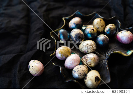 Colored chicken and quail eggs of pink, silver, golden and blue color on black 62390394