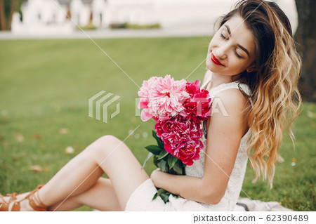 Elegant and stylish girl in a summer garden Elegant and stylish girl in a summer garden 62390489