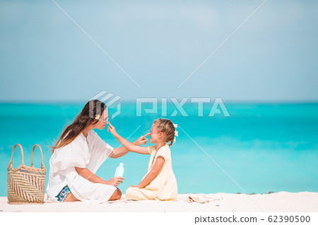 Young mother applying sun cream to daughter nose on the beach. Sun protection Young mother applying sun cream to daughter nose on the beach. Sun protection 62390500
