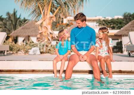 Happy family of four in outdoors swimming pool 62390895