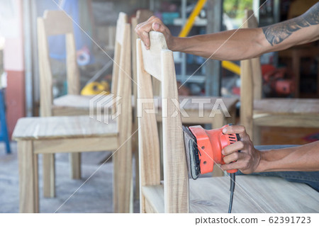 Carpenter Using Electric Sander for wood at his Carpenter Using Electric Sander for wood at his 62391723