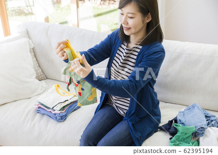 Young housewife folds children's clothes 62395194