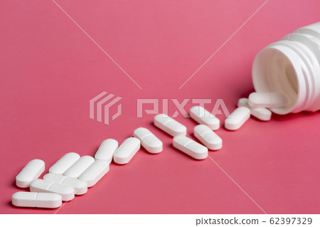 Plastic white bottles of pills on a pink background of scattered white pills Plastic white bottles of pills on a pink background of scattered white pills 62397329