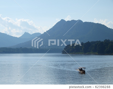 local transport boat sailing on brown water of MEKONG river in LAOS under warm summer sunlight with green hills in background plenty of copy space for natural adventure vacation tour advertisement local transport boat sailing on brown water of MEKONG river in LAOS under warm summer sunlight with green hills in background plenty of copy space for natural adventure vacation tour advertisement 62398288