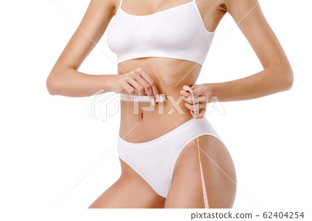 Slim tanned woman's body over gray background - waist measurement 62404254