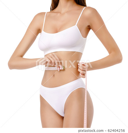 Slim tanned woman's body over gray background - waist measurement 62404256