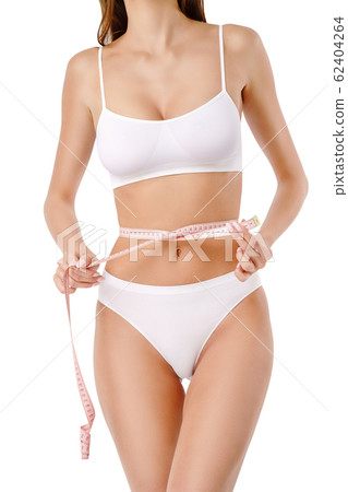 Slim tanned woman's body over gray background - waist measurement 62404264