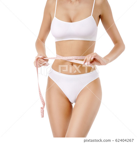 Slim tanned woman's body over gray background - waist measurement 62404267