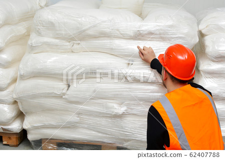 The Manager makes an inventory of flour in bags in the warehouse. A worker checking stock in a grocery warehouse. Counting physical inventory of groceries. The Manager makes an inventory of flour in bags in the warehouse. A worker checking stock in a grocery warehouse. Counting physical inventory of groceries. 62407788